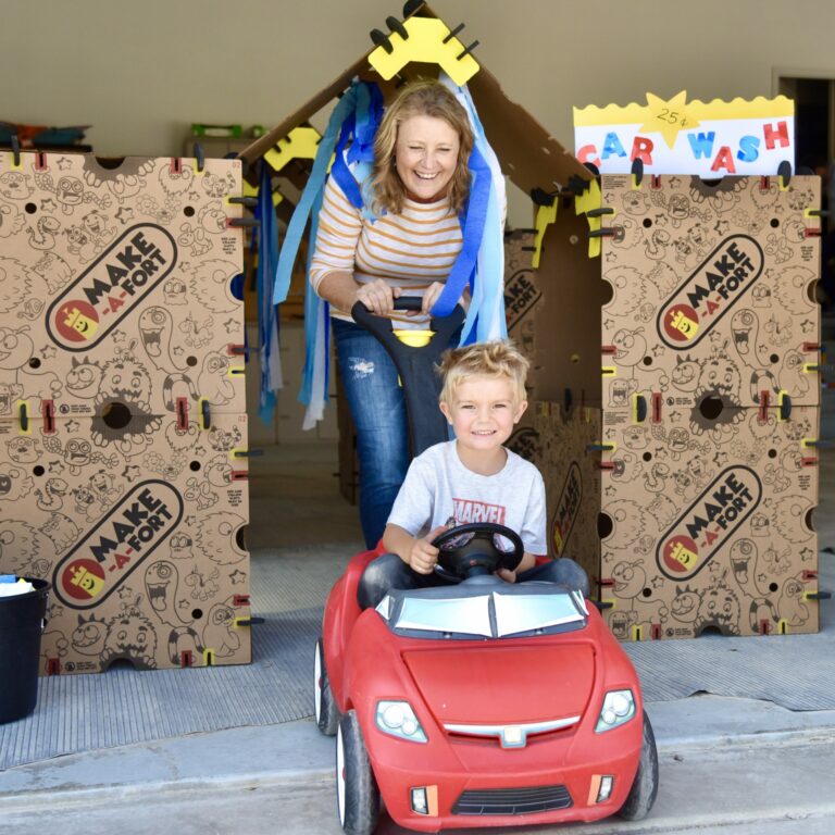 Grandma and grandson playing inside a cardboard car wash